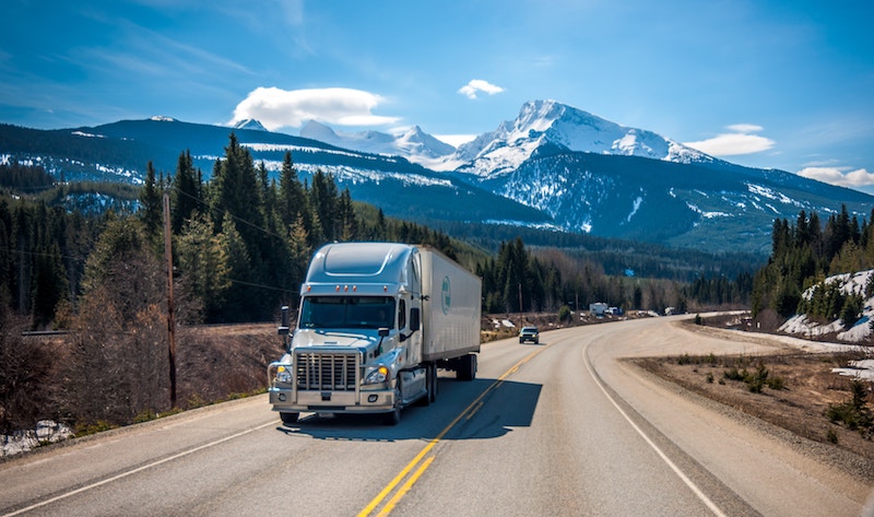 Truck driving along mountainside highway.